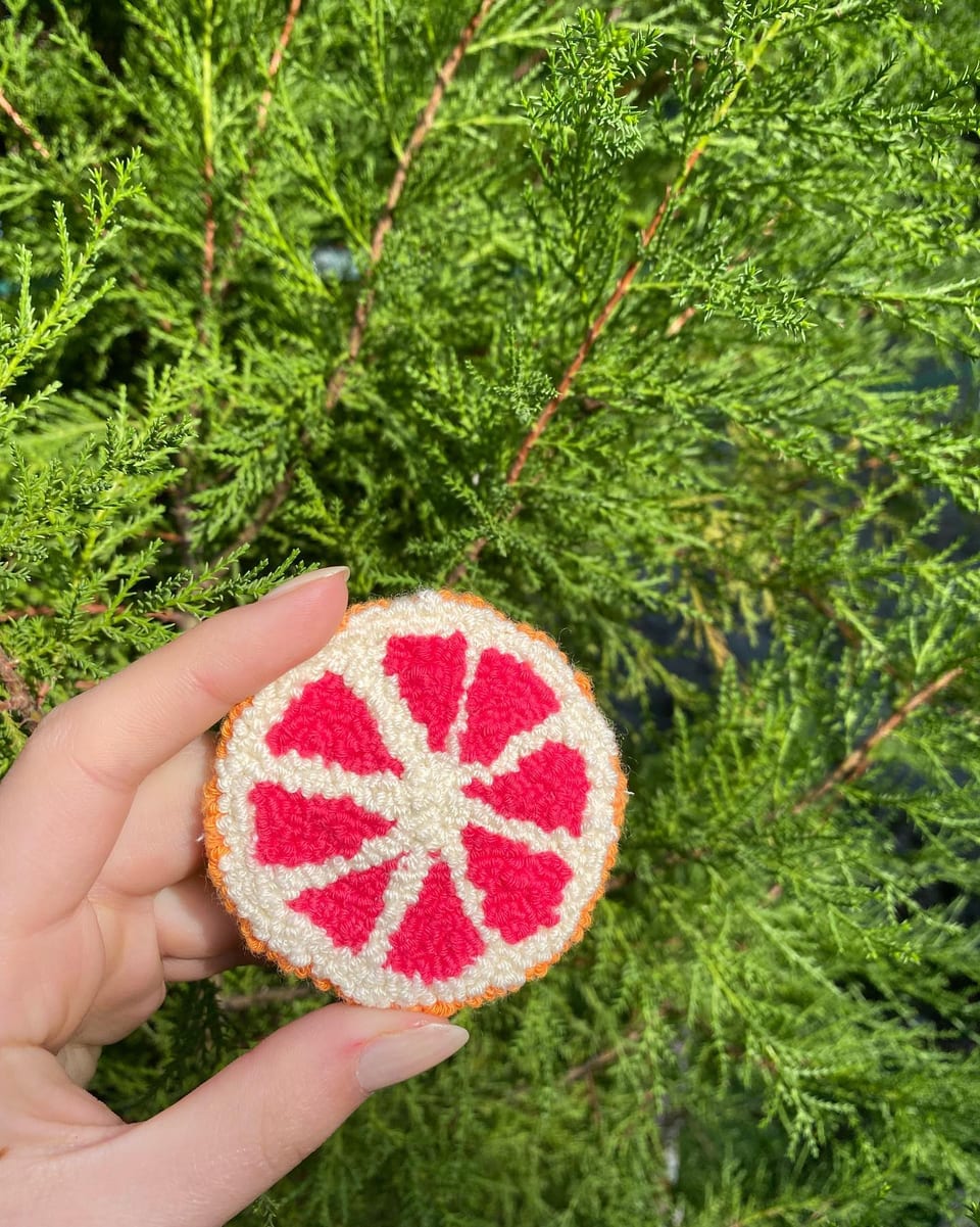 Pembe greyfurt dilimi punch nakış toka, elde yakın çekim