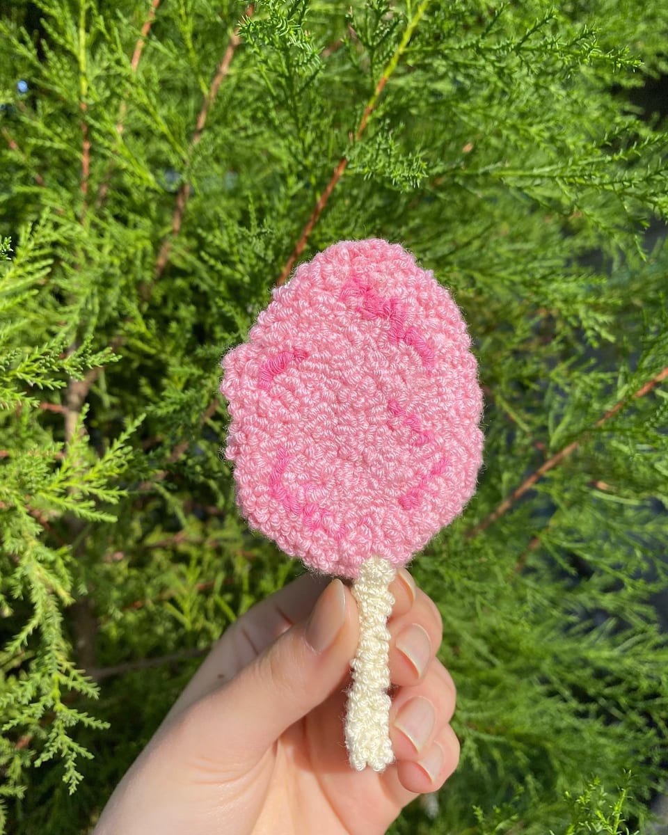 Krem çubuklu pembe pamuk şeker punch nakış toka, elde yakın çekim