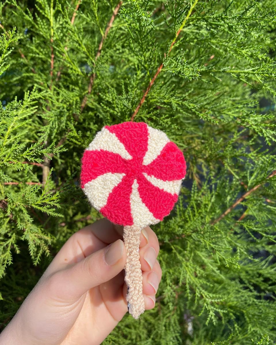 Kırmızı-beyaz spiral desenli lolipop punch nakış toka, elde yakın çekim