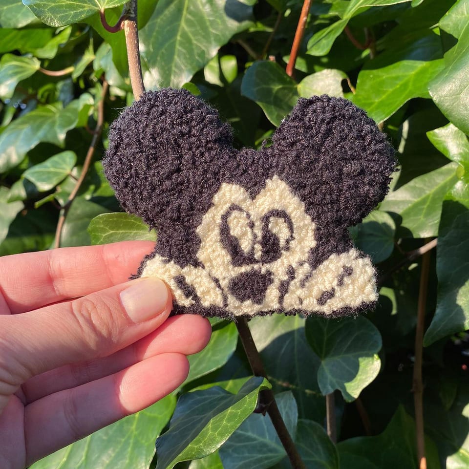 Siyah kulaklı, krem yüzlü gülen Mickey Mouse punch nakış toka, elde yakın çekim