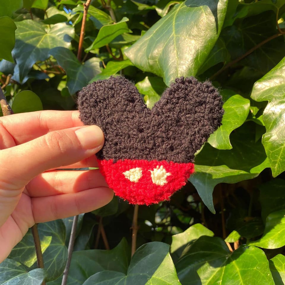 Siyah kulaklı silüet ve beyaz düğmeli kırmızı şortlu Mickey Mouse punch nakış toka, elde yakın çekim