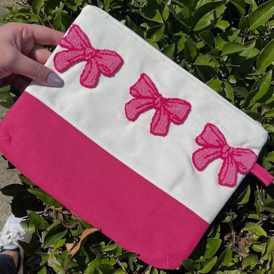 Fiyonklu punch clutch çanta elde, yeşil yaprakların önünde